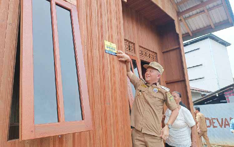 Bupati Gunung Mas Jaya S Monong saat masangkan peneng ke rumah program bedah rumah, Selasa, 3 Juni 2025. (FOTO: RISKA YULYANA)