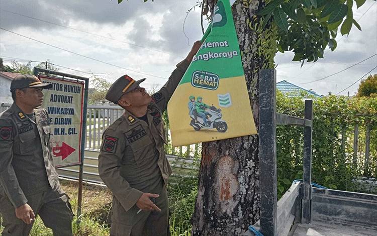 Tim patroli melepas media luar berupa spanduk yang terpasang di pohon. (FOTO:SATPOLPP KALTENG)