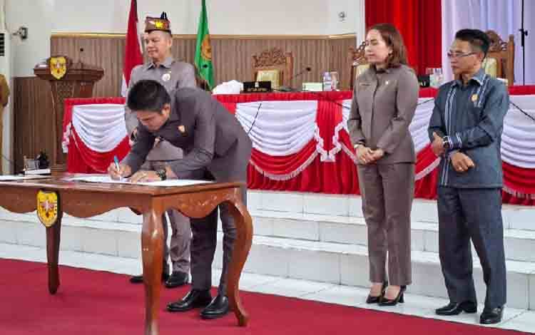 Ketua DPRD Gunung Mas Binartha saat menandatangani persetujuan bersama dengan kepala daerah terkait 3 raperda, Senin, 30 Juni 2025. (FOTO: RISKA YULYANA)