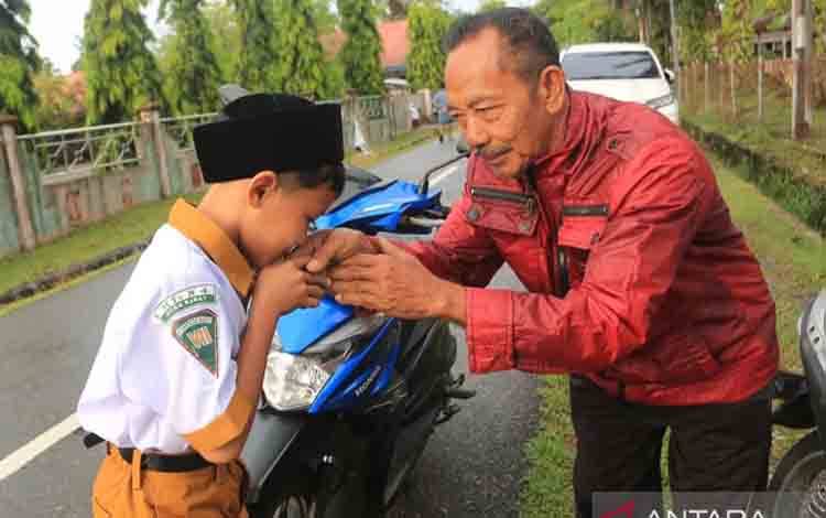 Siswa berpamitan kepada ayahnya setibanya di sekolah, Madrasah Tsanawiyah Negeri (MTsN) 4 Aceh Barat Desa Suak Timah, Samatiga, Aceh Barat, Aceh, Senin (14/7/2025). Menteri Kependudukan dan Pembangunan Keluarga/Badan Kependudukan dan Keluarga Berencana Nasional (Kemendukbangga/BKKBN) Wihaji menerbitkan surat edaran (SE) Nomor 7 Tahun 2025 tentang Gerakan Ayah Mengantar Anak di Hari Pertama Sekolah. ANTARA FOTO/Syifa Yulinnas/rwa.