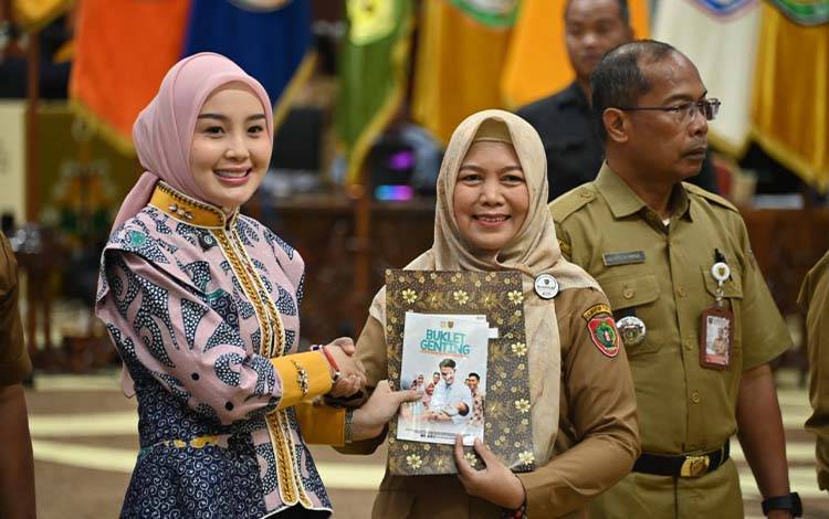 Ketua TP-PKK Kalteng yang juga Ketua Tim Pembina Pos Pelayanan Terpadu (Posyandu), Aisyah Thisia Agustiar Sabran menyerahkan buket Genting secara simbolis. (FOTO: SETDA KALTENG)