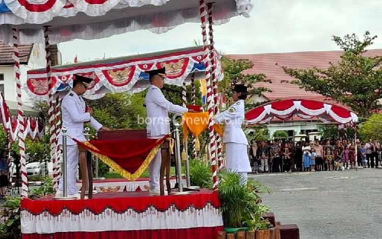 Bupati Gunung Mas saat menyerahkan Bendera Merah Putih kepada petugas Paskibraka, Minggu, 17 Agustus 2025. (FOTO: RISKA YULYANA)