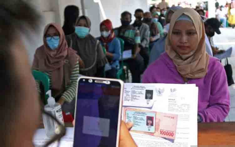 Petugas memotret warga penerima bantuan sosial dalam pelayanan penyaluran bantuan sosial di Kantor Pos Bandar Lampung, Lampung, Kamis (14/4/2022).ANTARA FOTO/Ardiansyah/foc