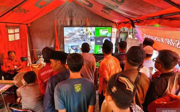 Sejumlah warga dan keluarga korban melihat proses evakuasi melalui layar televisi di Posko SAR gabungan, di wilayah Ponpes Al Khoziny, Buduran, Sidoarjo, Jumat (3/10/2025). ANTARA/Naufal Ammar Imaduddin