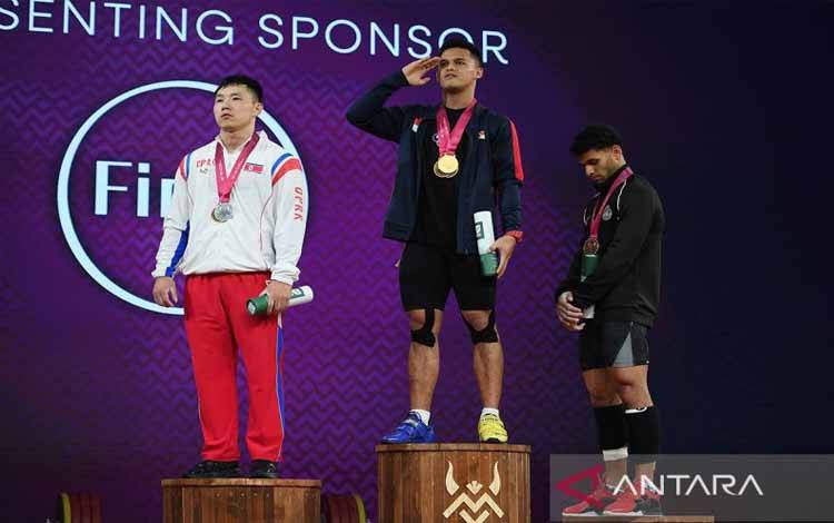 Lifter Indonesia peraih medali emas Rizki Juniansyah (tengah) hormat saat menyanyikan lagu Indonesia Raya usai menjuarai kelas 79 kilogram putra kejuaraan Dunia Angkat Besi IWF (IWF World Championship) 2025 di Forde, Norwegia, Selasa (7/10/2025) dini hari WIB. ANTARA FOTO/Xinhua/He Canling/sgd/pri