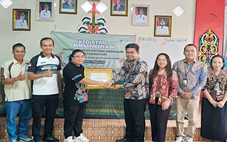 Kepala BPS Barito Timur, Yulianto, menyerahkan piagam penghargaan sebagai Desa Cantik Terbaik se Kalteng tahun 2025 kepada Kepala Desa Bagok Risa Ramayati, di Balai Pertemuan Desa Bagok, Jumat, 12 Desember 2025. (FOTO: AGUSTINUS BOLE MALO)