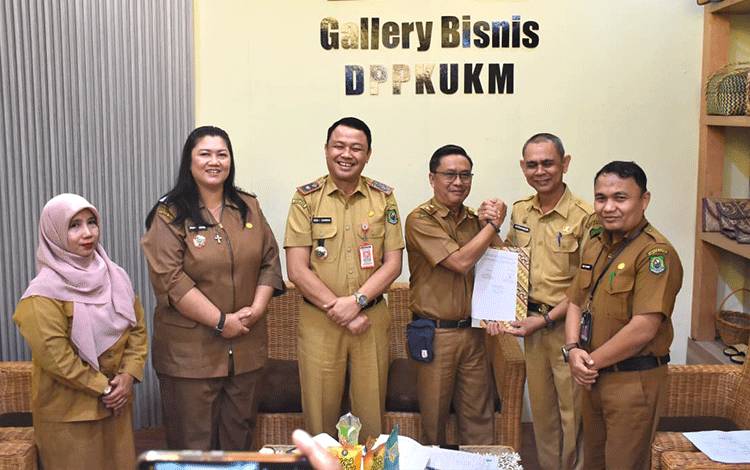 Kepala Dinas Perdagangan, Perindustrian, Koperasi, dan UKM Kabupaten Kapuas Apendi menyerahkan pengelolaan Pasar Ikan kepada Kepala Dinas Ketahanan Pangan dan Perikanan Kabupaten Kapuas Vitrianson, disaksikan Sekretaris Daerah Kabupaten Kapuas Usis I. Sangkai dan Asisten II Sekretariat Daerah, di DPPKUKM Kabupaten Kapuas, Selasa, 23 Desember 2025. (FOTO: Diskominfo Kps)