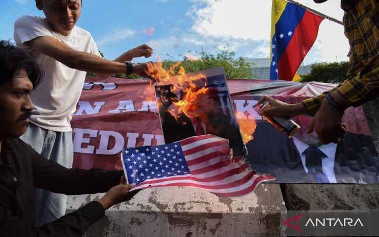 Pengunjuk rasa dari berbagai aliansi membakar bendera AS dan poster bergambar presiden AS Donald Trump saat menggelar aksi solidaritas untuk Venezuela di depan Kedutaan Besar Amerika Serikat, Jakarta, Selasa (6/1/2026). Dalam aksi solidaritas tersebut mereka mengecam tindakan penyerangan dan penangkapan terhadap Presiden Venezuela Nicolas Maduro berserta istrinya oleh Amerika Serikat dan meminta agar Indonesia untuk menyatakan sikap resmi, serta mendukung rakyat Venezuela menentukan nasib negara