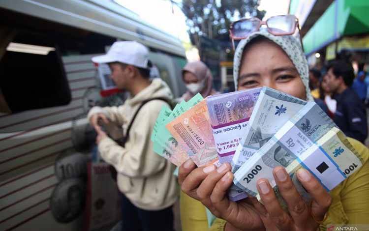 Warga menunjukan uang rupiah baru yang baru saja ditukarkan pada mobil kas keliling Bank Indonesia (BI) di Pasar Palmerah, Jakarta, Senin (18/3/2024). ANTARA FOTO/Muhammad Iqbal