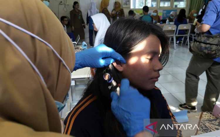 Tenaga medis Dinas Kesehatan Tangerang Selatan memeriksa telinga salah satu siswi SMAN 6 Tangerang Selatan dalam agenda kick off CKG Sekolah, Senin (4/8/2025). (ANTARA/Andi Firdaus/am)