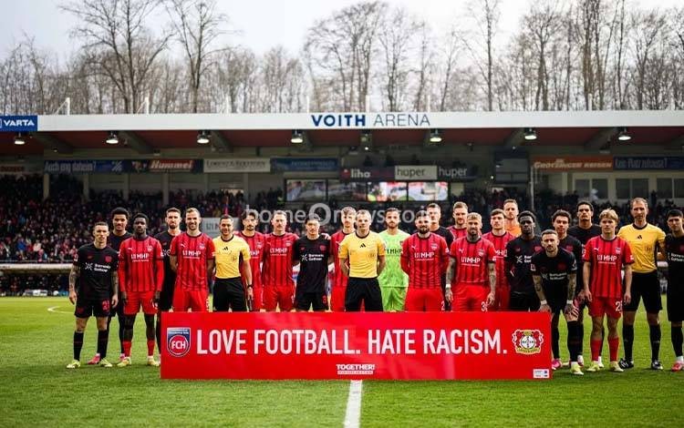 Pemain Bayer Leverkusen dan Heidenheim berfoto bersama sebelum pertandingan Liga Jerman di Stadion Voith-Arena, Heidenheim, Sabtu (21/3/2026) waktu setempat. (x.com/bayer04_en)