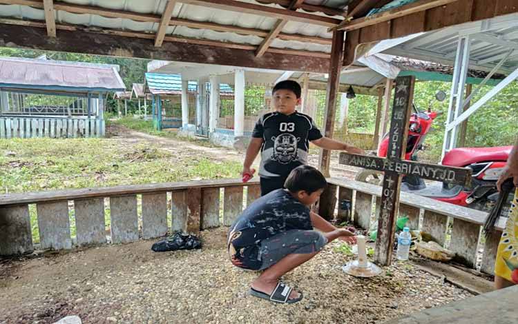 Aktivitas anak-anak sedang menghidupkan lilin di makam keluarganya (Foto:MARINI)