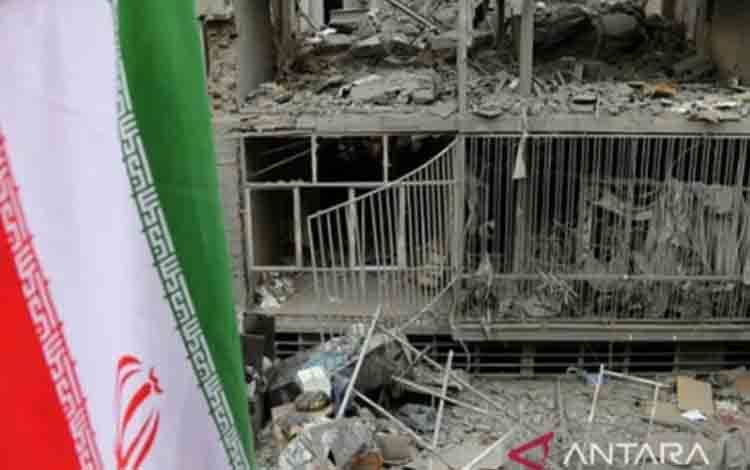 Arsip - Bendera Iran terlihat dengan latar belakang kerusakan besar di distrik Javadiyeh dan Beryanak akibat serangan AS-Israel di Teheran pada 15 Maret 2026. (ANTARA/Fatemeh Bahrami/Anadolu/pri.)