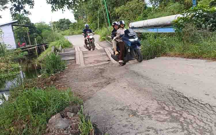 Warga melintas di jembatan kayu Jalan Walter Condrat, Sabtu, 13 Juni 2026. (FOTO: DEWIP)