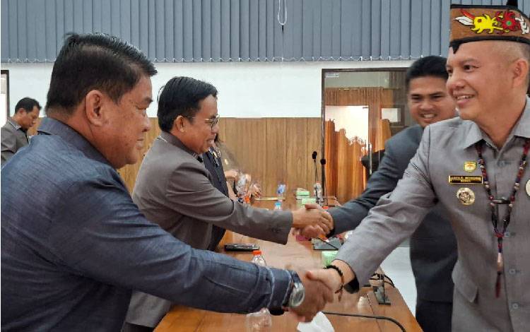 Bupati Gunung Mas Jaya S Monong saat bersalaman dengan anggota DPRD Gunung Mas Yulius Agau. (FOTO: RISKA YULYANA)