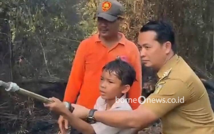 Lurah Langkai Muhamad Abidin bersama Jali, siswa SD yang ikut membantu penanganan karhutla di kawasan Langkai Permai I, Palangka Raya. (FOTO: IST)